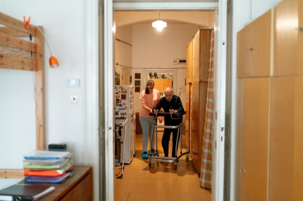 Fizjoterapeuta pomaga starszemu pacjentowi chodzić z balkonikiem